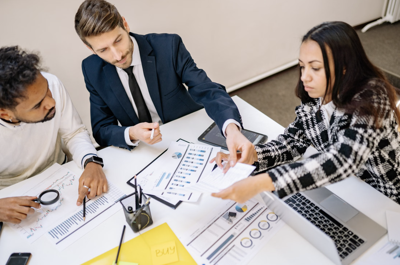 Diverse business team collaborating around a table reviewing charts, analytics, and strategy documents during a planning meeting
