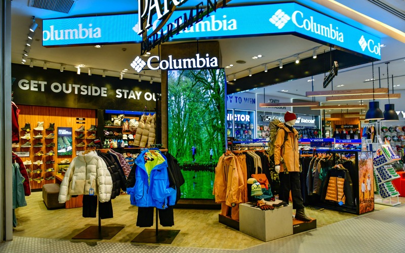 Columbia shop with jackets on mannequins and racks beneath lighted Columbia signs.